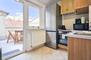 A kitchen with a refrigerator, oven, microwave, and wooden cabinets. - MidTerm - Rooftop Serenity Apartment 3 (Budapest)