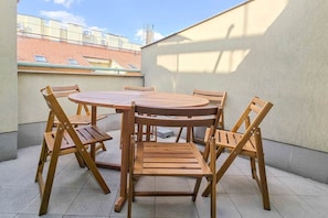 A round wooden table with six chairs on a tiled patio. - MidTerm - Rooftop Serenity Apartment 3 (Budapest)