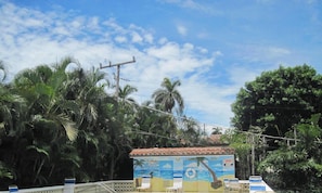 A beachside building with a mural, surrounded by palm trees and a clear sky. - Steps to the Beach and all that Delray has to offer. (Delray Beach)