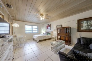 A well-lit room with a bed, a desk with a computer, a chair, a coffee table, and a sofa.