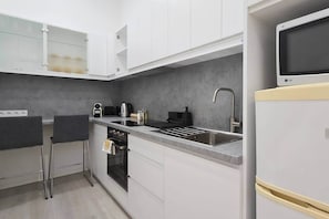 A compact kitchen with a built-in oven, a sink, and a microwave. - MidTerm - CityCenter67 Apartment (Budapest)