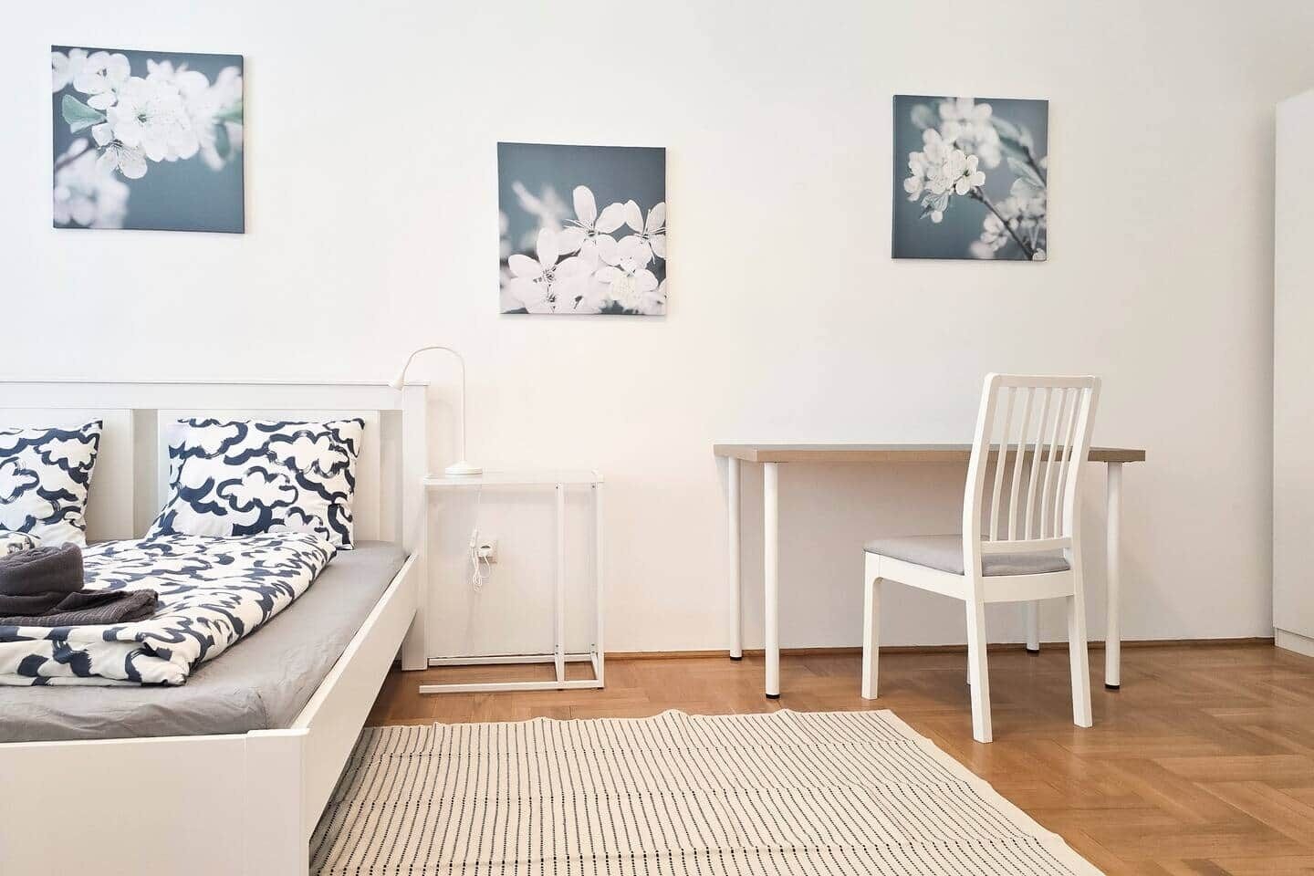 Un dormitorio con una cama, un escritorio y una silla. Hay tres cuadros colgados en la pared.