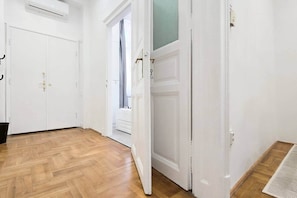 A hallway with wooden flooring, white doors, and an air conditioning unit. - MidTerm - CityCenter67 Apartment (Budapest)