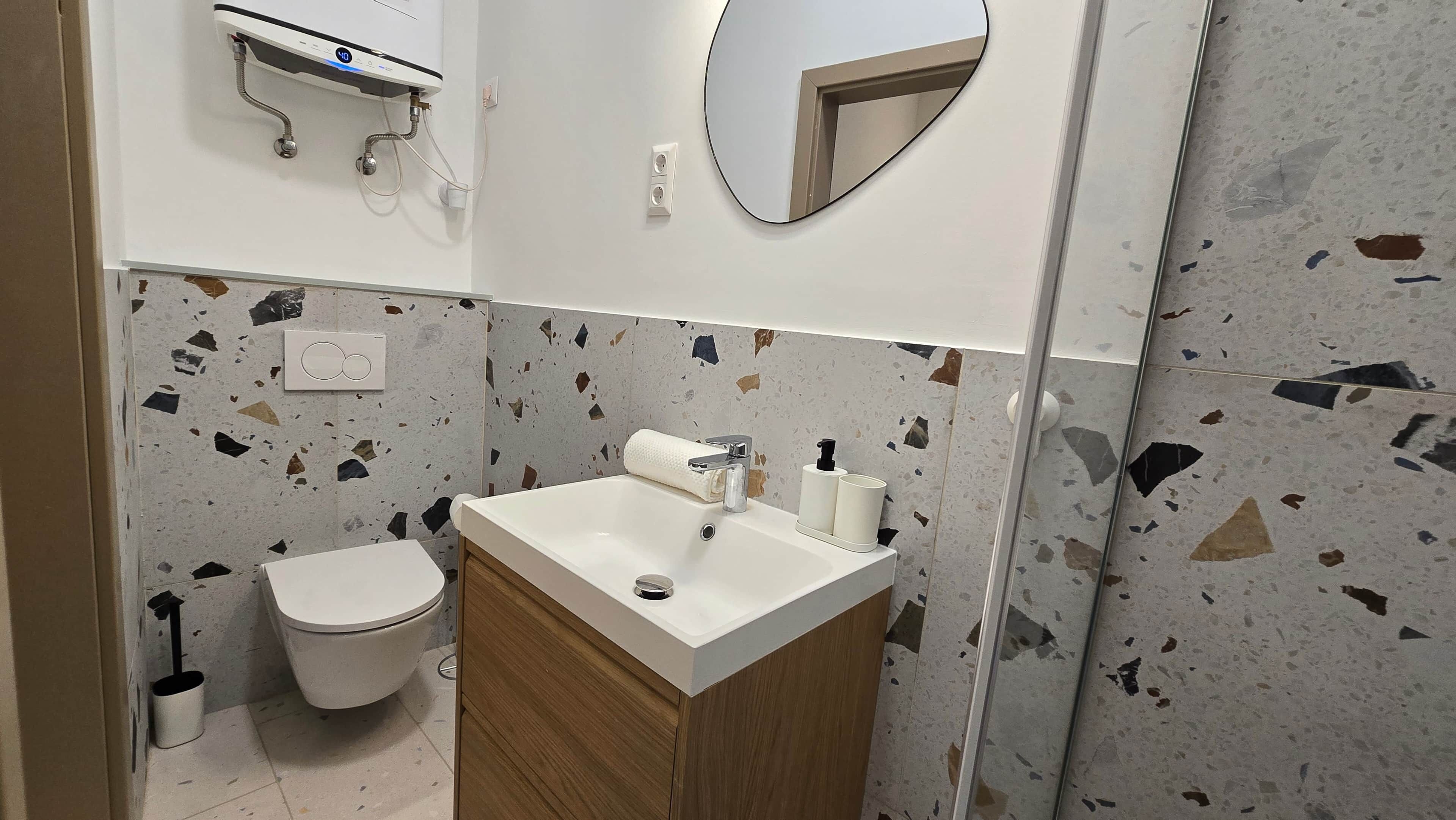 A bathroom with a toilet, sink, and mirror.
