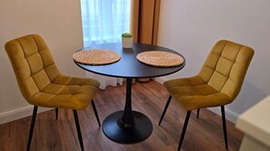 Ein Zimmer mit zwei senffarbenen Stühlen um einen runden Tisch mit gewebten Untersetzern.