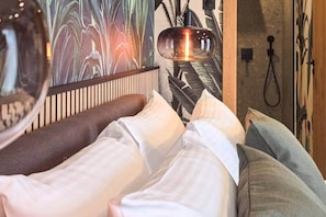 A bed with white and grey bedding, a wooden headboard, and a wall with a large plant mural. - IMCT - Urban Jungle Apartments 07 (Budapest)