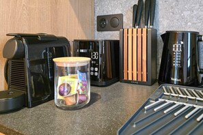 A kitchen counter with a coffee maker, a toaster, a kettle, and a glass jar with snacks. - IMCT - Urban Jungle Apartments 07 (Budapest)