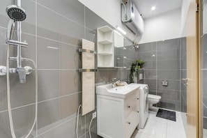 A modern bathroom with a shower, sink, toilet, and a mirror above the vanity. - MidTerm - Rózsa Apartments - Mira (Budapest)