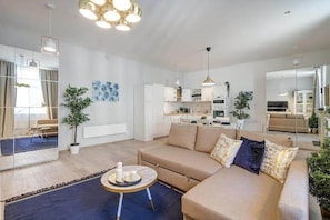 A modern living room with a sofa, a coffee table, and a dining area. - MidTerm - Rózsa Apartments - Mira (Budapest)
