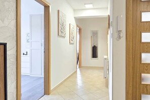 A hallway with a door on the right, a light fixture, and a framed picture on the wall. - MidTerm - Rooftop Serenity Apartment 2 (Budapest)