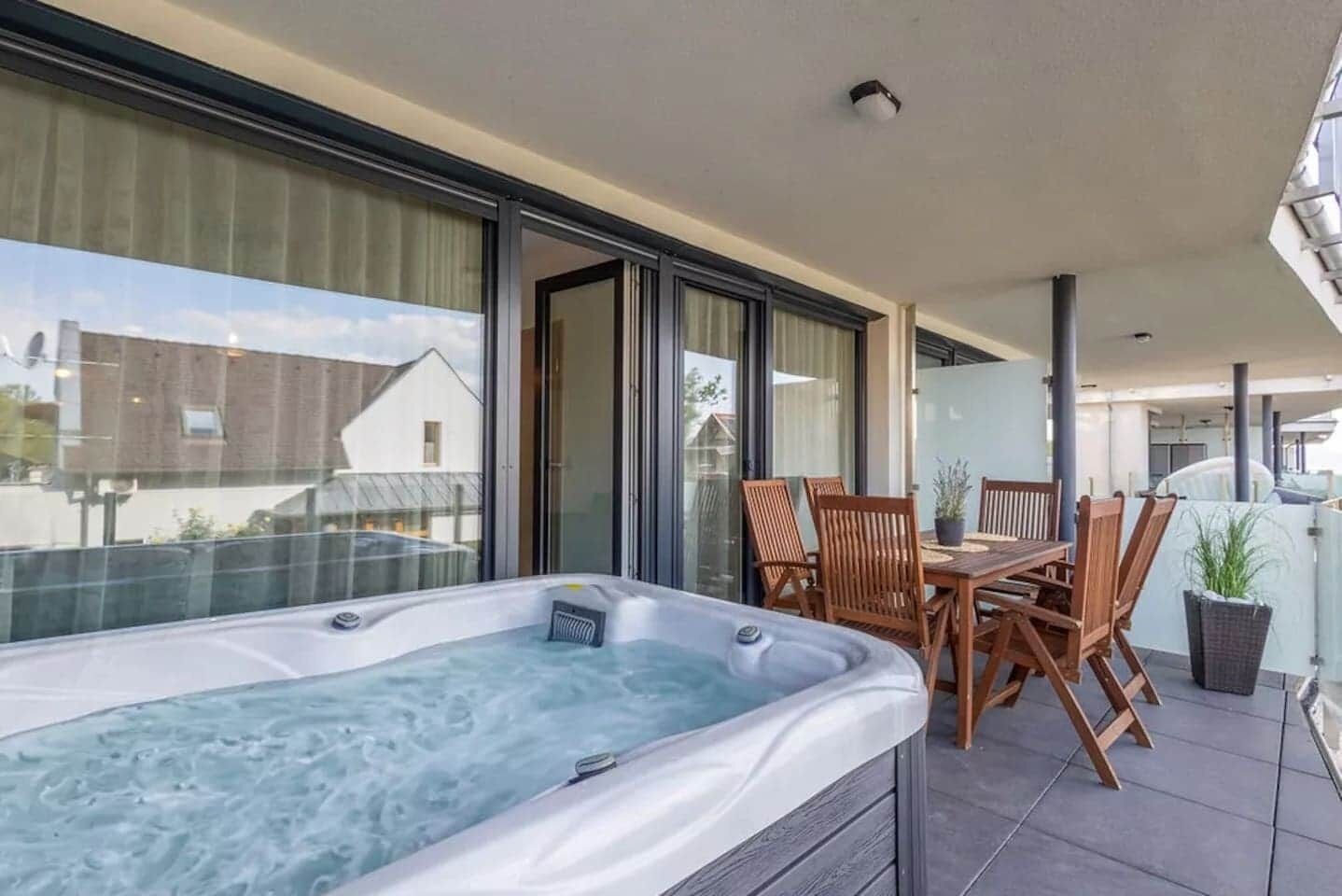 Un balcon avec un jacuzzi, des chaises en bois et une table.