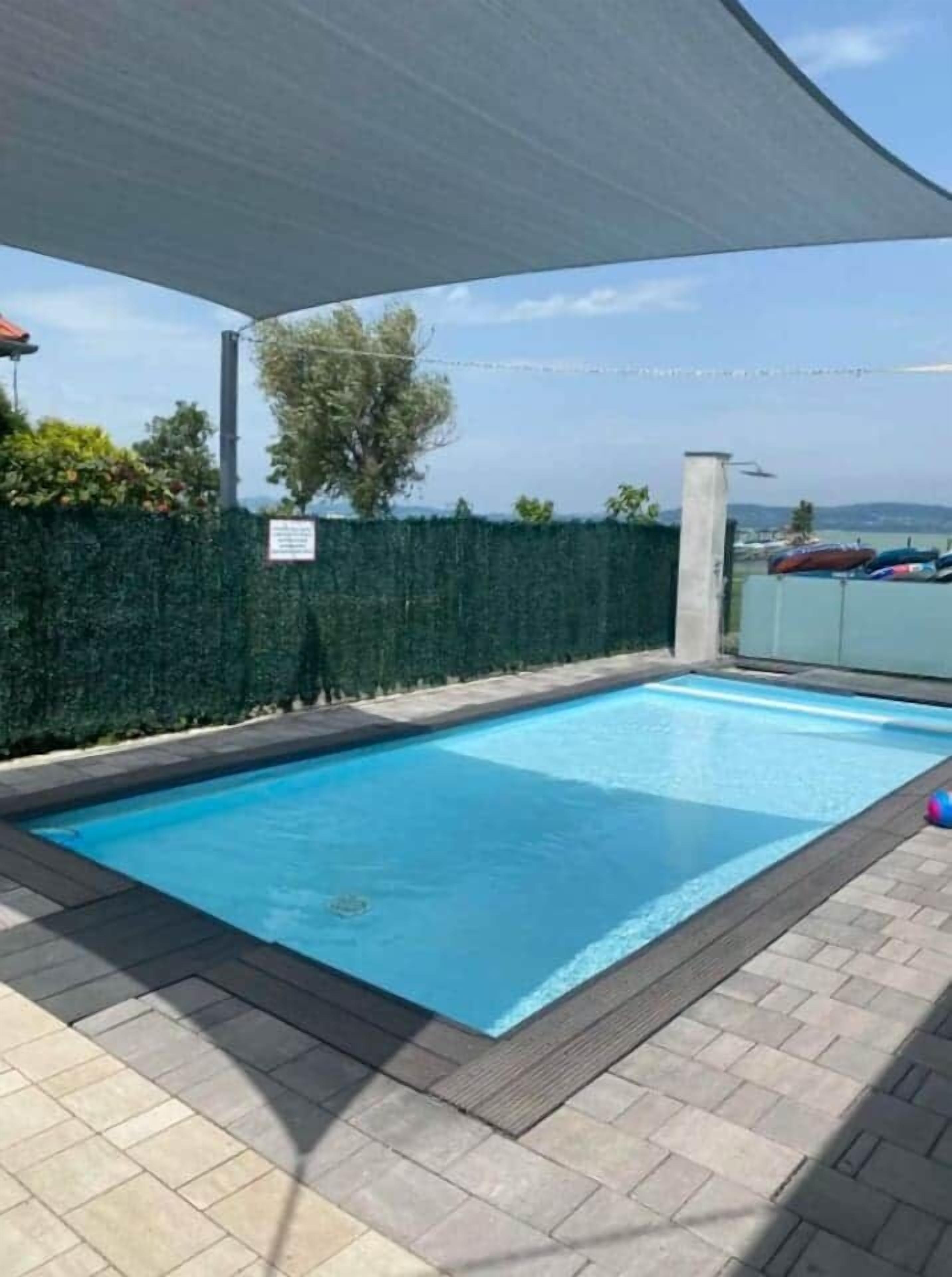 A rectangular swimming pool with a tiled deck surrounding it.