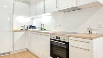 A modern kitchen with white cabinets, a built-in oven, and a stainless steel range hood.