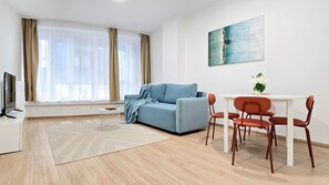 Un salon moderne avec un canapé, une table à manger et des chaises, un téléviseur et un tableau accroché au mur.