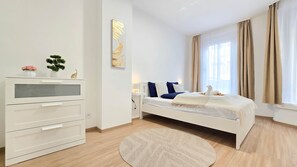 Une chambre à coucher moderne avec un lit, une table de chevet et une commode blanche.