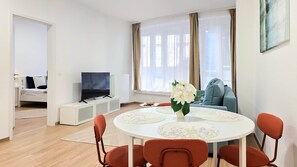 Un salon moderne avec un téléviseur, un canapé et un coin repas.