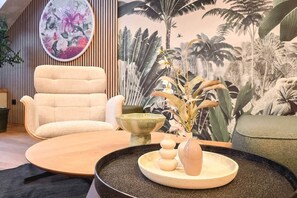 A modern living room with a beige sofa, a round wooden coffee table, and a decorative vase with dried flowers. - IMCT - Urban Jungle Apartments 02 (Budapest)