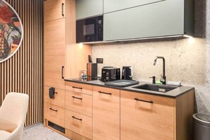 A compact kitchen with a microwave, toaster, and sink. - IMCT - Urban Jungle Apartments 02 (Budapest)
