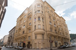 A corner building with multiple floors, large windows, and a prominent corner entrance. - IMCT - Riverside Deluxe Apartment (Budapest)