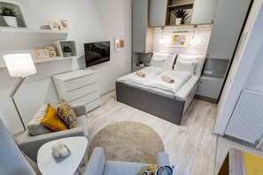 A compact bedroom with a bed, bedside tables, a desk, a chair, a lamp, and a small rug. - IMCT - Riverside Deluxe Apartment (Budapest)