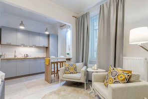 A modern living space with a kitchen, a sofa set, and a small table. - IMCT - Riverside Deluxe Apartment (Budapest)