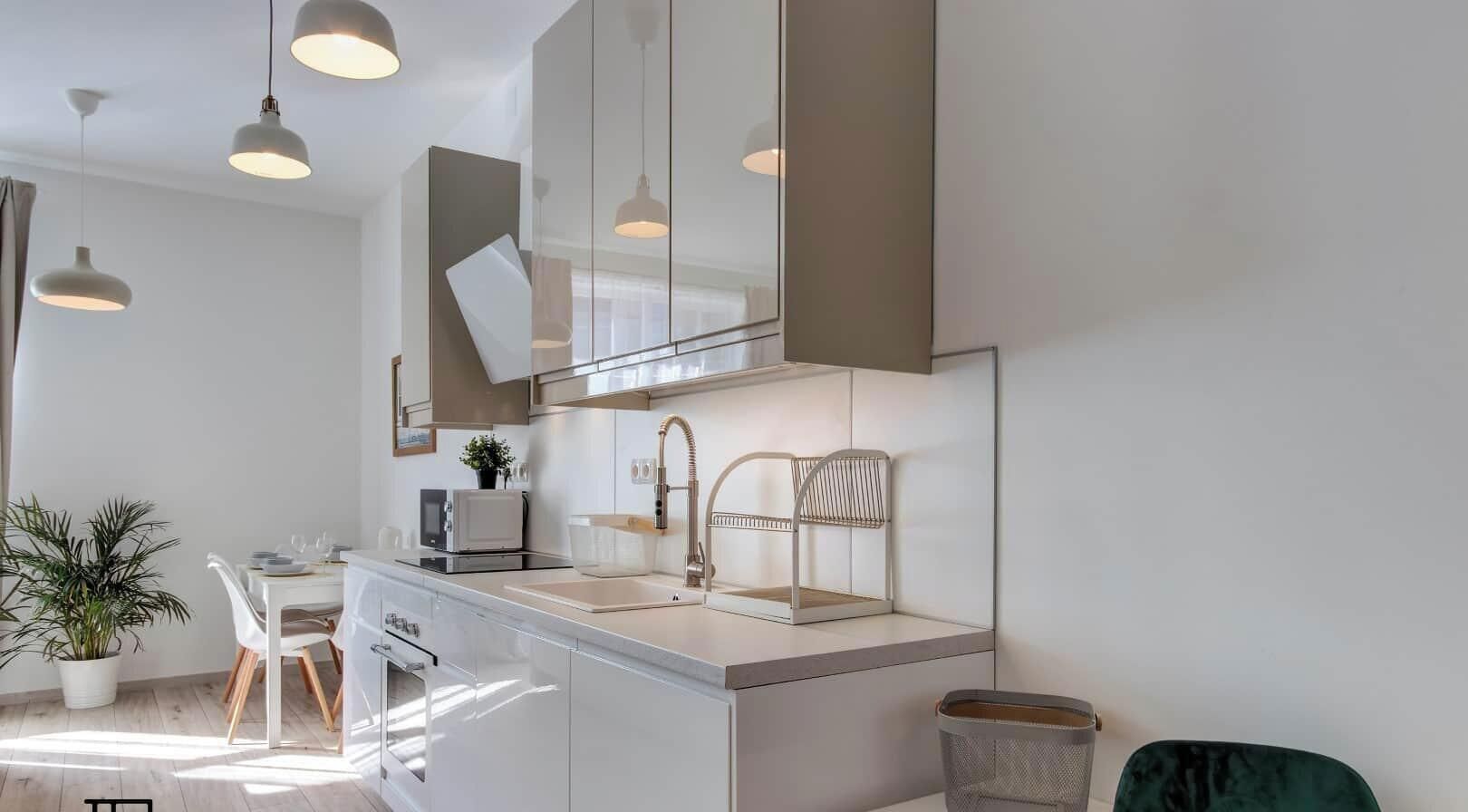 Una cocina moderna con una isla central, iluminación colgante y un espejo grande sobre el lavamanos.