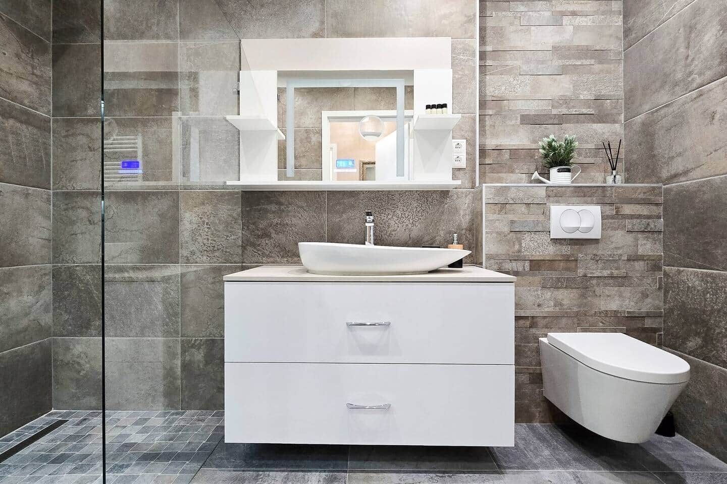 A modern bathroom with a glass shower enclosure, a white vanity with a vessel sink, and a toilet.