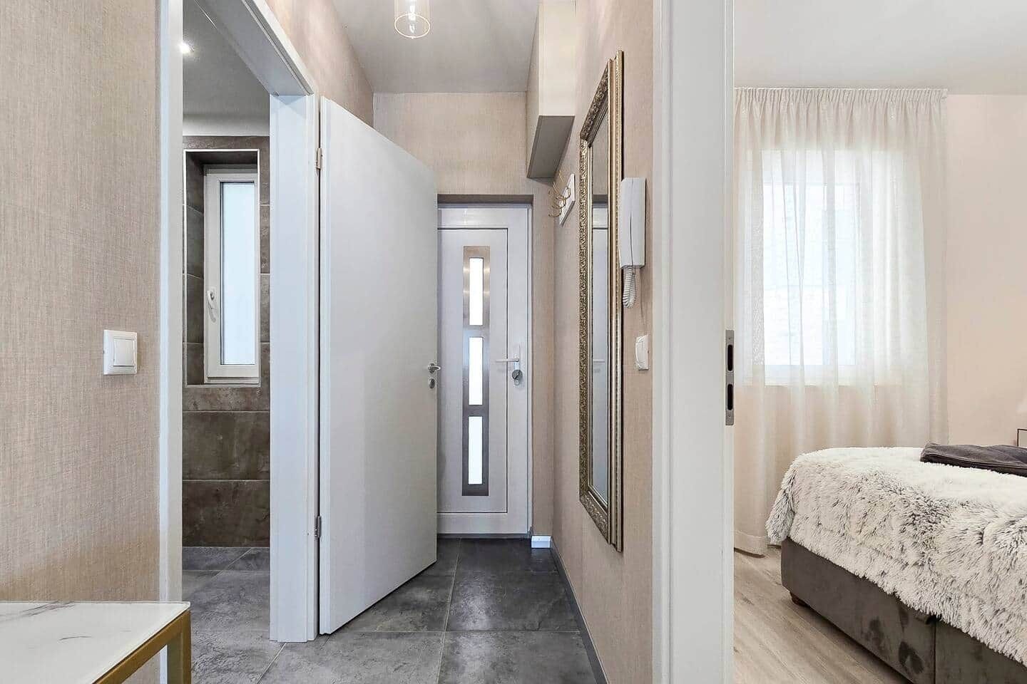 A bedroom with a bed, a door, and a mirror.