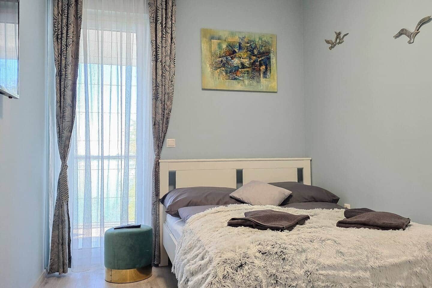 Una camera da letto con un letto, tende, un quadro e un piccolo tavolo.