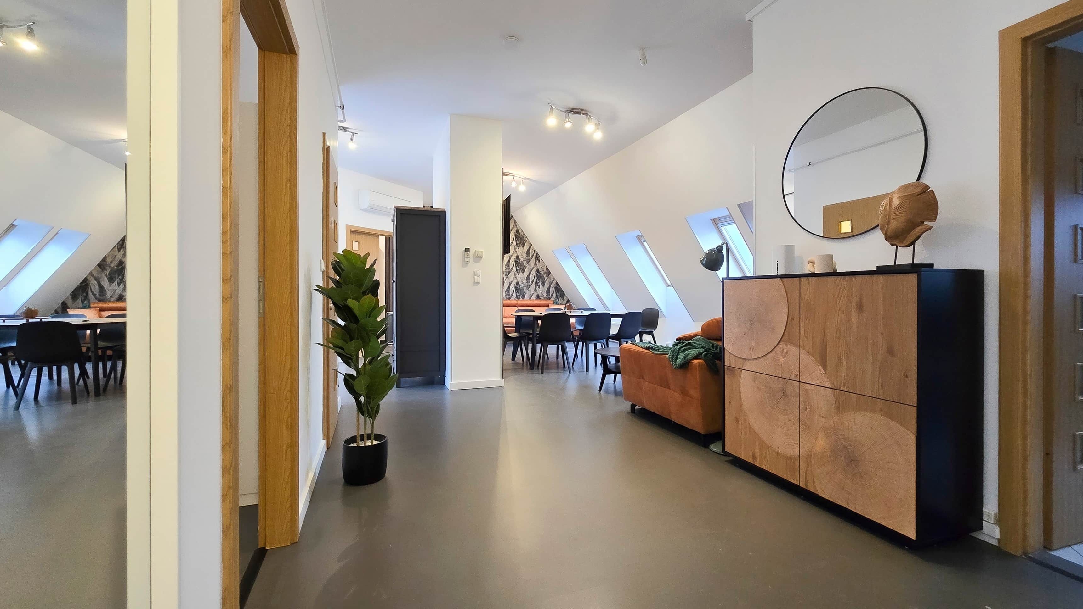 A modern interior with a dining area, a sofa, a cabinet, and a potted plant.