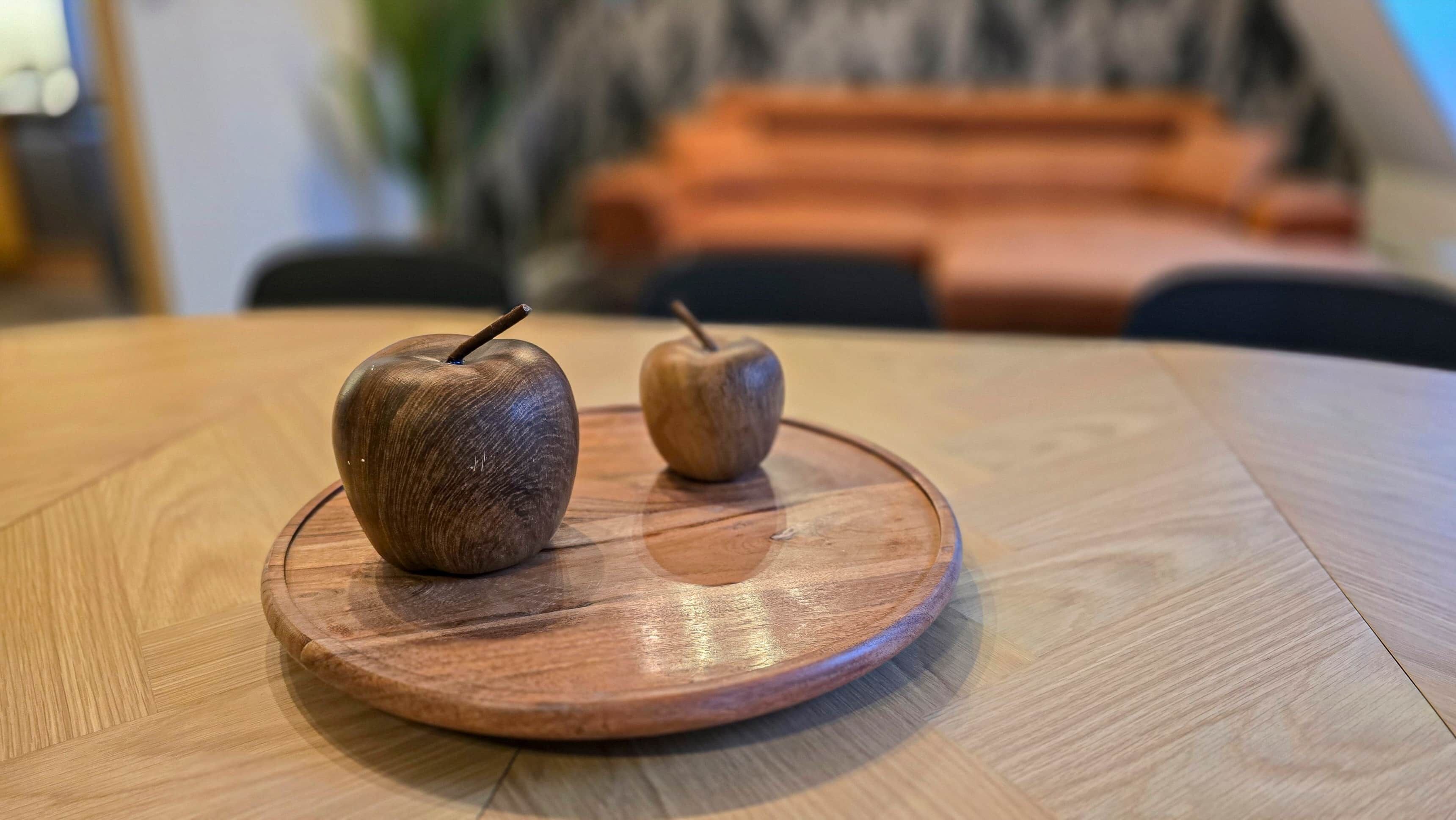 Two wooden apples on a round wooden table.