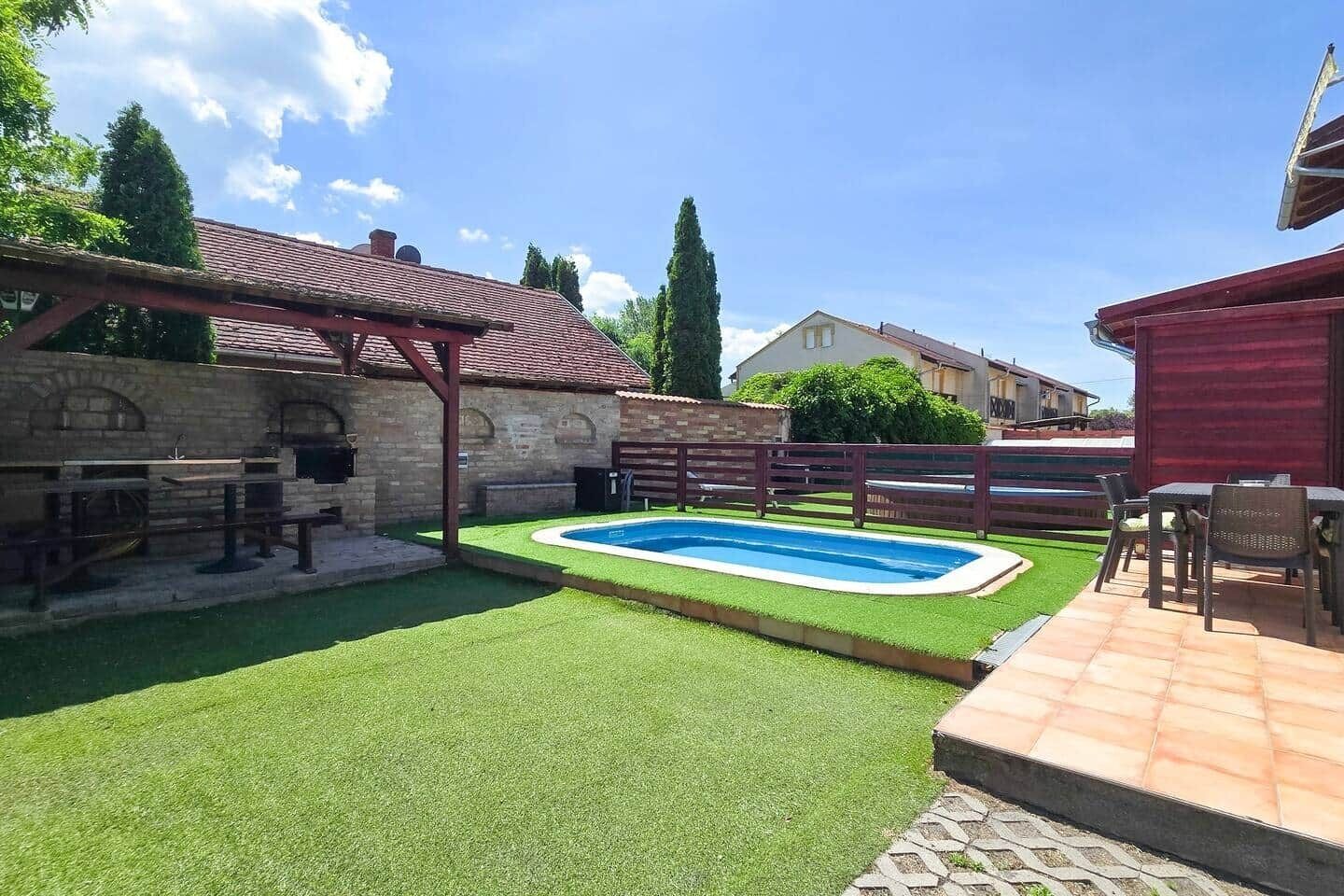 A backyard with a swimming pool, a barbecue area, and a patio with outdoor furniture.