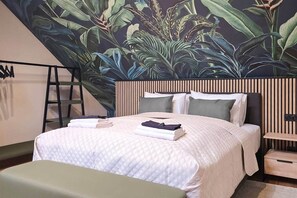 A bedroom with a bed, pillows, a bedside table, and a wall mural. - IMCT - Urban Jungle Apartments 10 (Budapest)