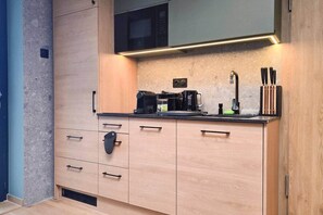 A modern kitchen with a built-in microwave, coffee maker, and knife block. - IMCT - Urban Jungle Apartments 10 (Budapest)