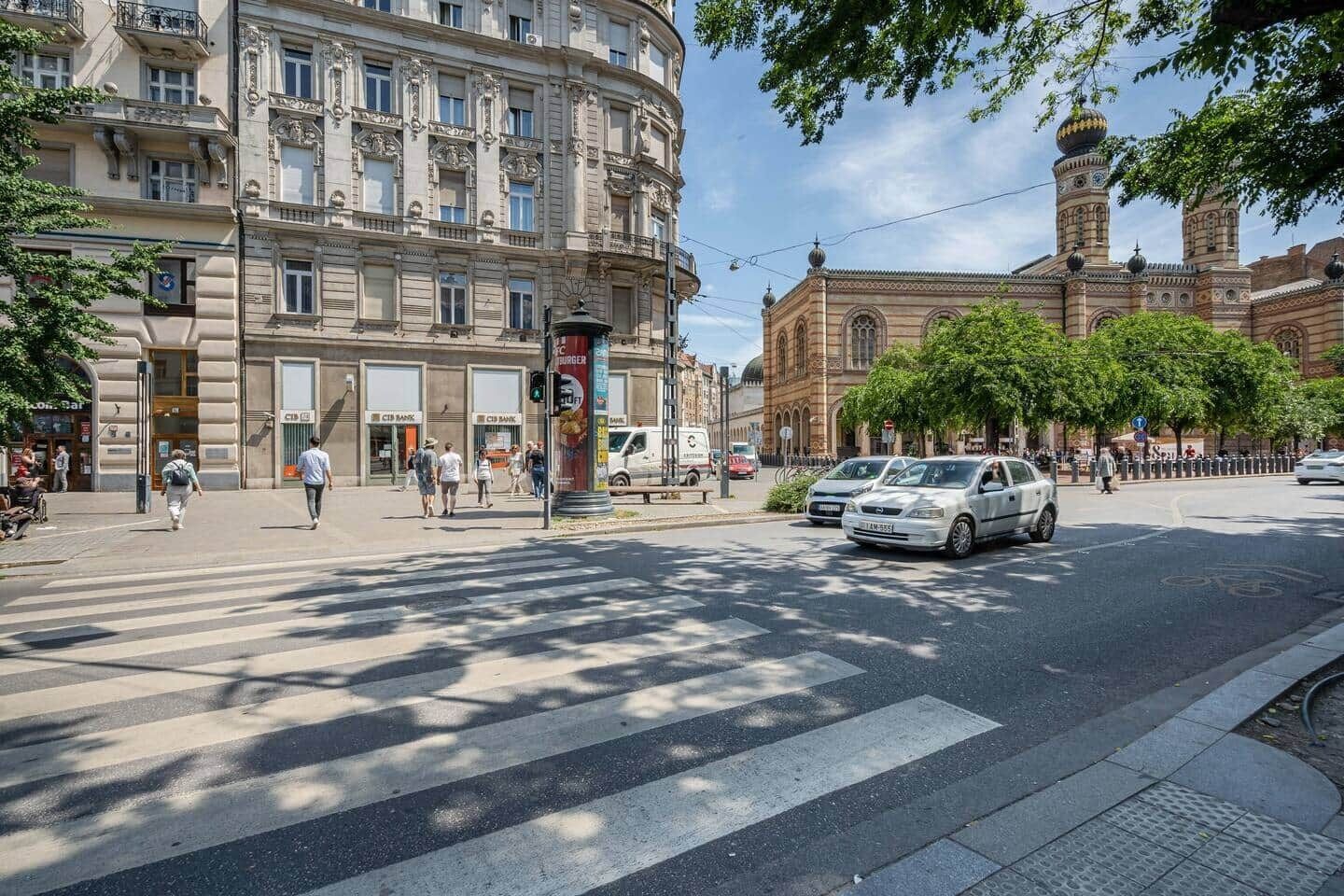 Eine Straßenscharte mit einer Fußgängerampel, einem weißen Auto und einem Gebäude mit einer Kuppel.