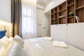 Ein Hotelzimmer mit Bett, Schrank, Nachttisch und einem fenster mit Vorhängen.