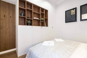 A bedroom with a bed, a wardrobe, and a built-in shelving unit. - IMCT - Sky Way Apartment (Budapest)