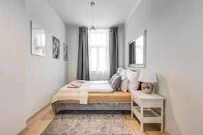 A bedroom with a bed, bedside table, lamp, and artwork on the walls. - MidTerm - Rózsa Apartments - Daniel (Budapest)