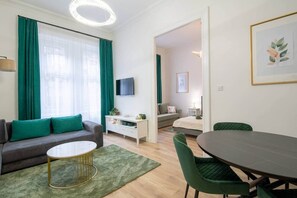 A modern living room with a sofa, coffee table, and dining area. - IMCT - Rose Apartment (Budapest)