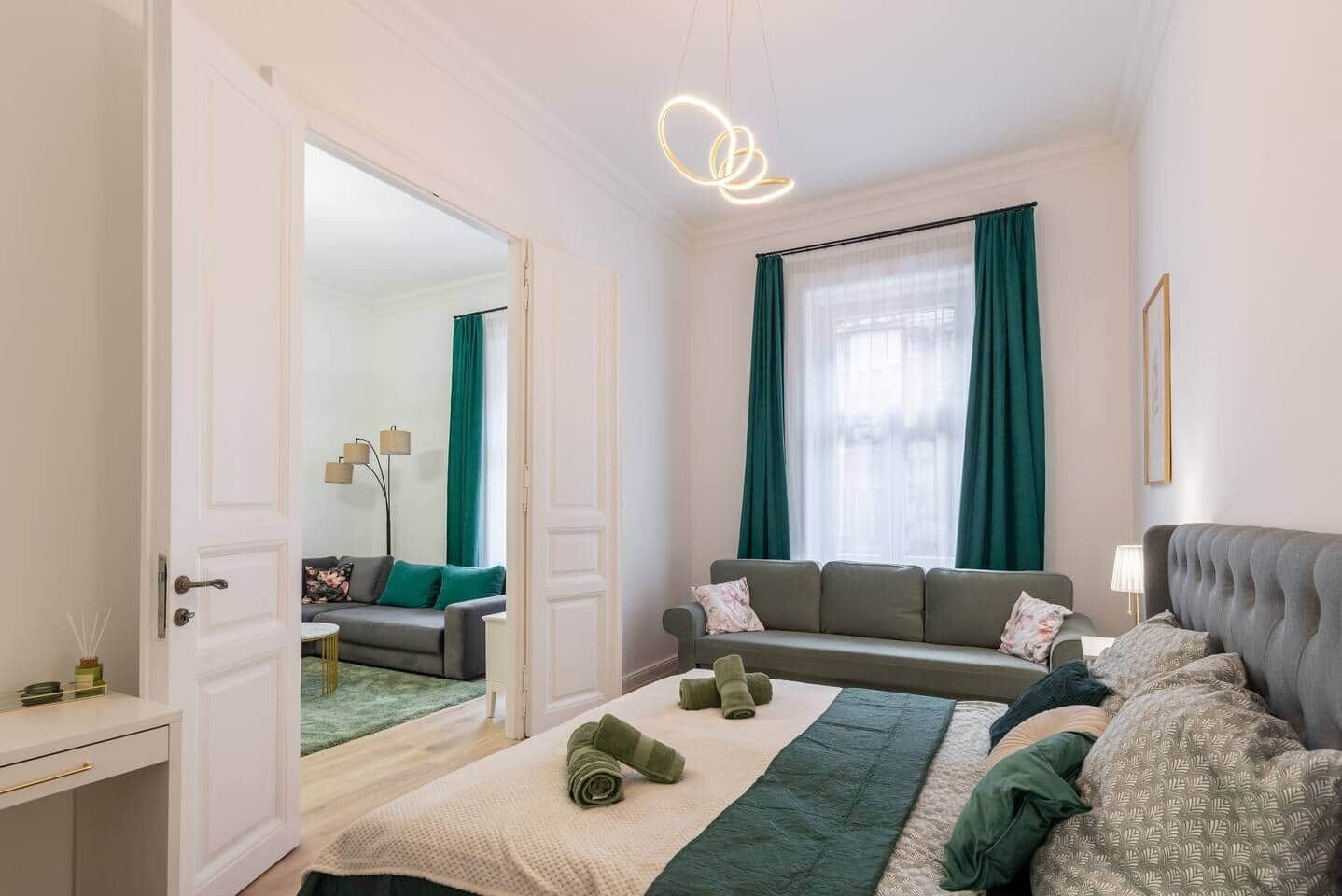 A modern hotel room with a sofa, a bed, a desk, and a mirror.