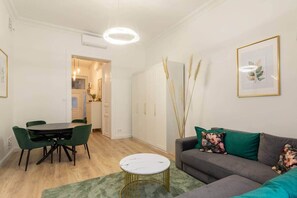 A modern living room with a dining area, a sofa with floral cushions, and a round coffee table. - IMCT - Rose Apartment (Budapest)