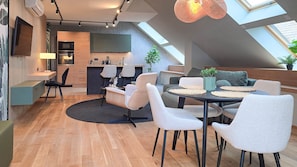 A modern loft-style living space with a kitchen, dining area, and seating area. - IMCT - Urban Jungle Apartments 04 (Budapest)