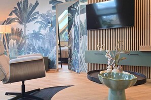 A modern living room with a flat-screen TV, a comfortable sofa, a decorative vase, and a wall with vertical wooden slats. - IMCT - Urban Jungle Apartments 04 (Budapest)