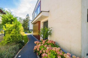 A modern building with a paved pathway leading to the entrance, surrounded by greenery and flowering plants. - LB - Silver Lodge 1 Siófok (Siófok)