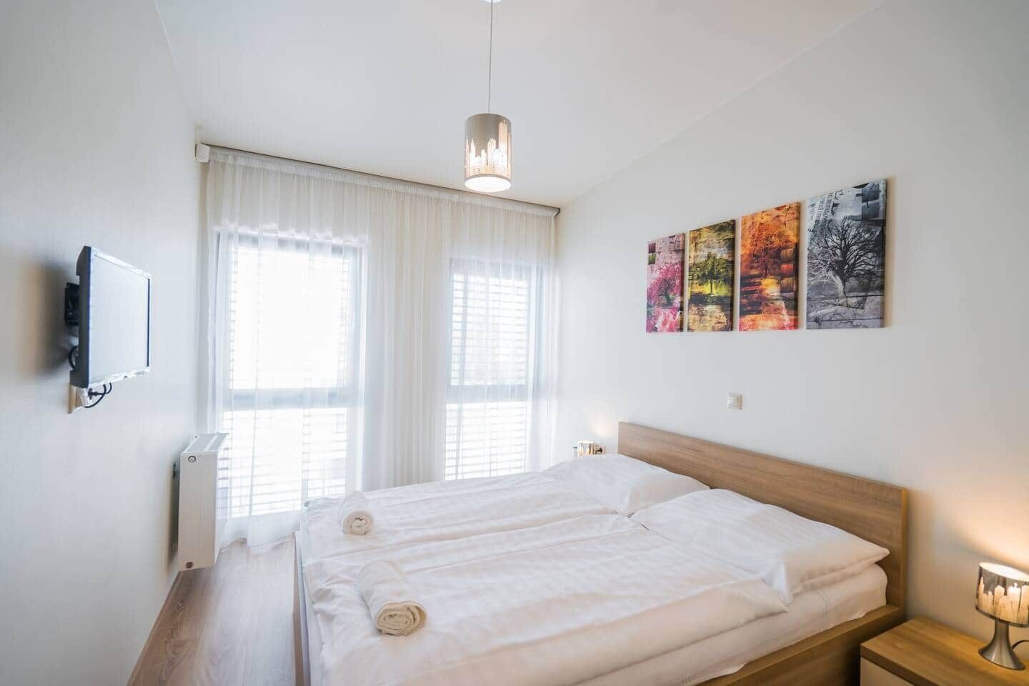 Un dormitorio con cama, televisión, radiador y una obra de arte en la pared.