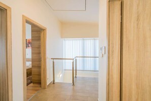 A hallway with wooden flooring, a metal railing, and a window with blinds. - LB - Silver Lodge 1 Siófok (Siófok)