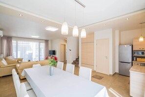A modern living room with a dining table, sofas, and a TV. - LB - Silver Lodge 1 Siófok (Siófok)