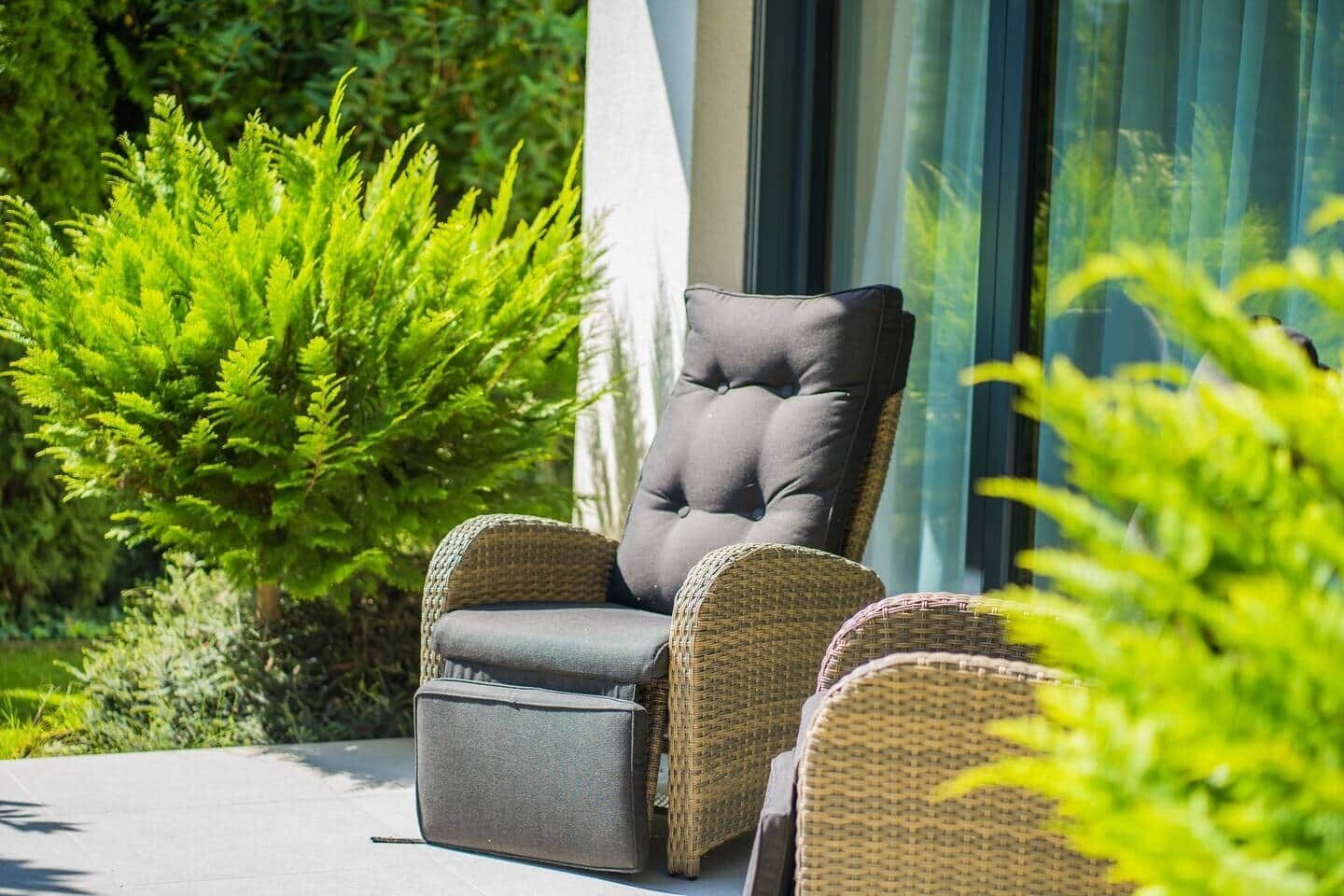 A single black cushioned chair with a high backrest and armrests, positioned on a concrete surface.