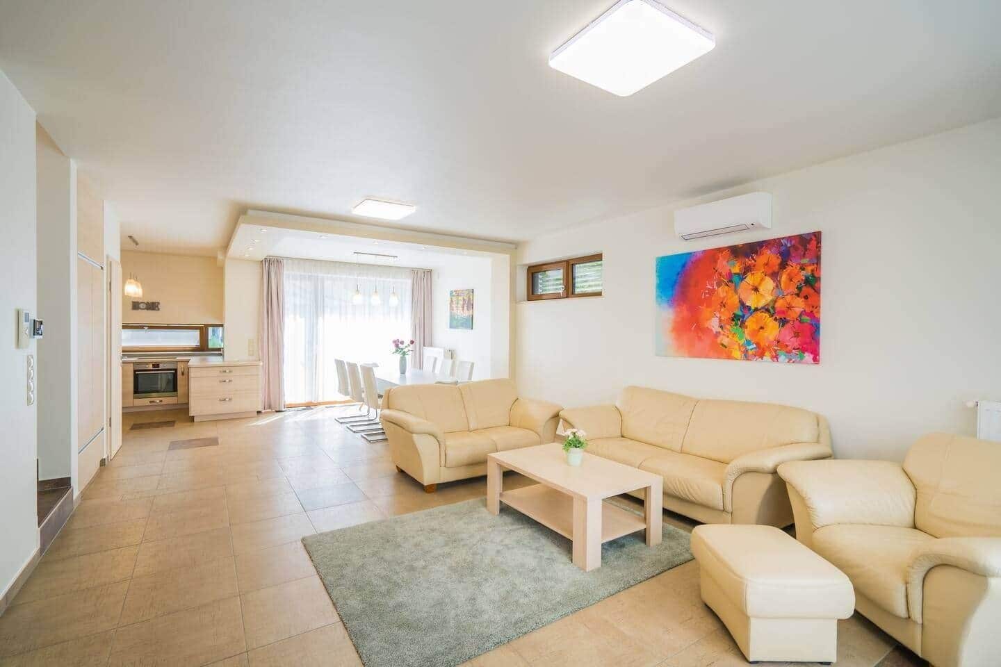 A modern living room with a sofa set, a coffee table, and a dining area with chairs.