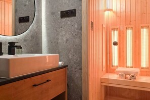 A modern bathroom with a granite countertop sink, a wooden cabinet, and a glass enclosure with a sauna. - IMCT - Urban Jungle Apartments 03 (Budapest)